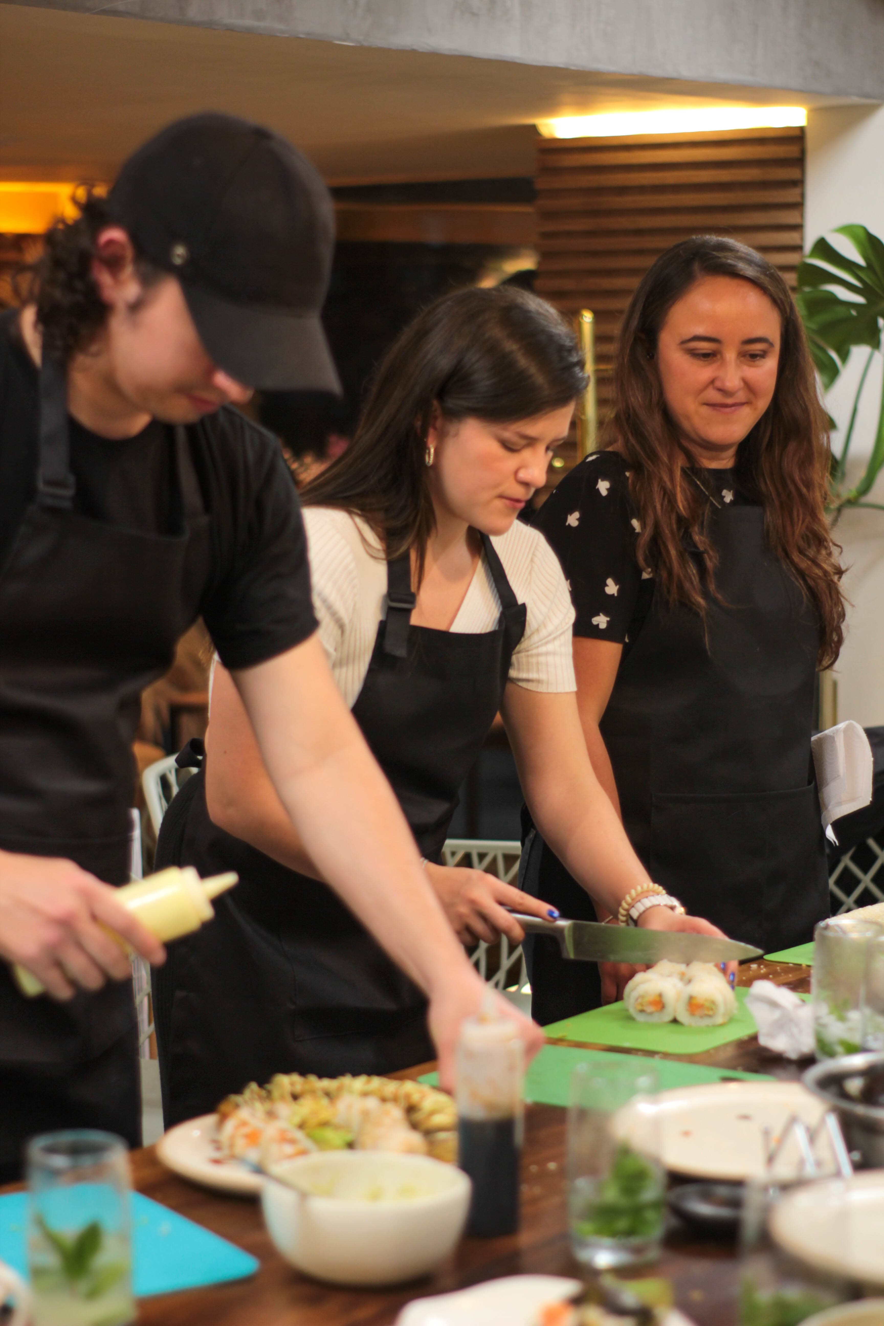 Participantes preparando y presentando rollos de sushi en equipo